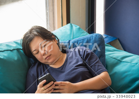Asia women 40s holding smartphone thinking on sofa 33948023