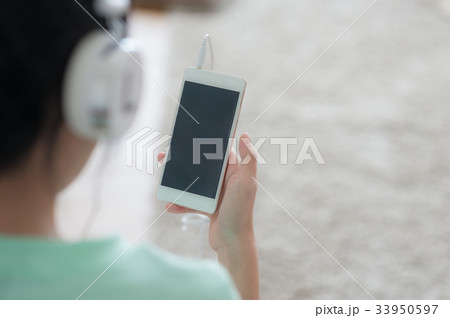 Young Asian woman listening music with smartphone Young Asian woman listening music with smartphone 33950597