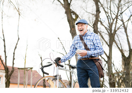 Senior man with smartphone and bicycle in town. 33952432
