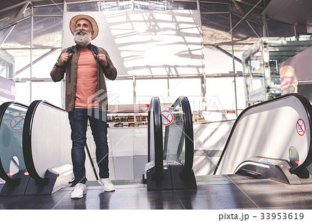 Beaming pensioner standing on escalator Beaming pensioner standing on escalator 33953619