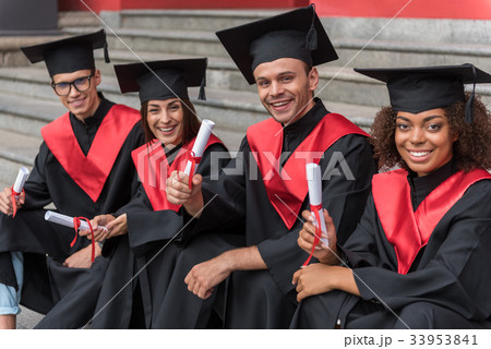 Glad young students sitting on steps in graduation 33953841