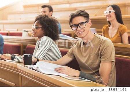 Cheerful male student sitting at lecture hall Cheerful male student sitting at lecture hall 33954141
