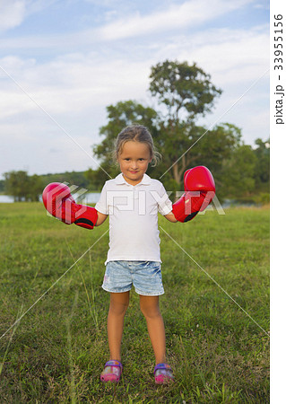 A young girl wearing red boxing gloves. A young girl wearing red boxing gloves. 33955156