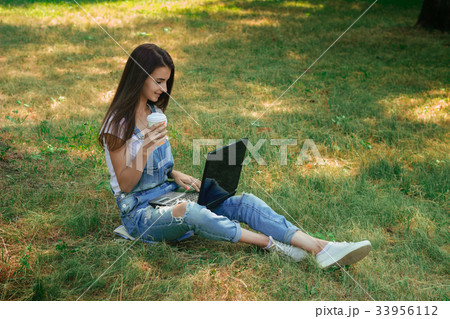beautiful girl sits on the grass, holding a cup of beautiful girl sits on the grass, holding a cup of 33956112