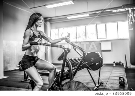 Fitness female using air bike for cardio workout 33958009
