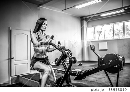 Fitness female using air bike for cardio workout Fitness female using air bike for cardio workout 33958010