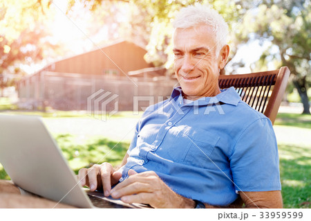 Senior man with notebook sitting in the park 33959599