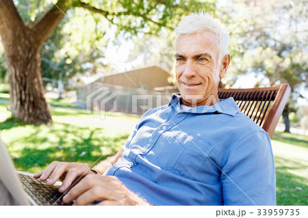 Senior man with notebook sitting in the park Senior man with notebook sitting in the park 33959735