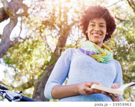Happy young woman with bicycle reading book Happy young woman with bicycle reading book 33959963