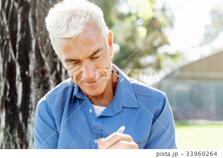 Senior man sittingin park while reading book 33960264