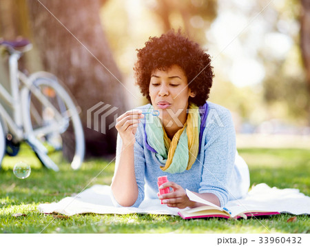 Beautiful woman blowing bubbles in park Beautiful woman blowing bubbles in park 33960432