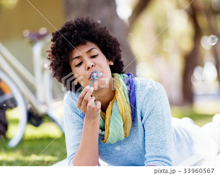 Beautiful woman blowing bubbles in park 33960567