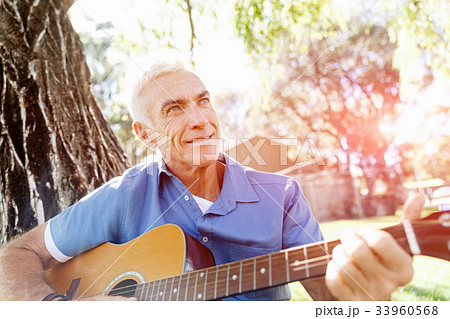 Senior man plying guitar outdoors Senior man plying guitar outdoors 33960568