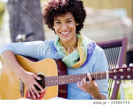 Woman playing guitar in park 33960743
