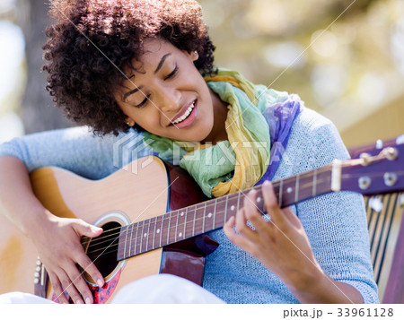 Woman playing guitar in park Woman playing guitar in park 33961128