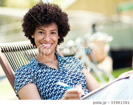 Beautiful young woman writing in her diary outdoors Beautiful young woman writing in her diary outdoors 33961381