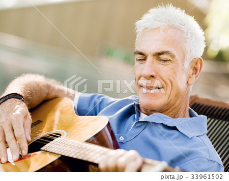 Senior man plying guitar outdoors 33961502