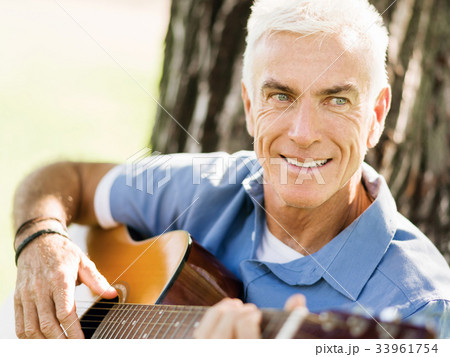 Senior man plying guitar outdoors 33961754