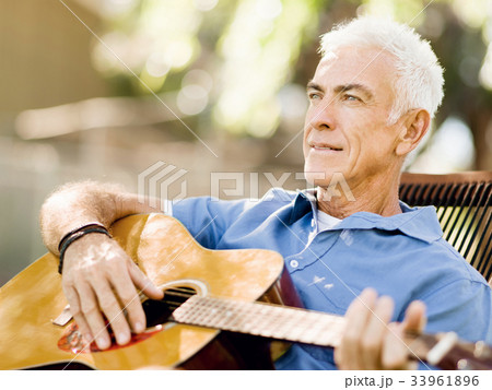 Senior man plying guitar outdoors 33961896