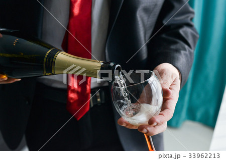 man filling decorated glass with champagne 33962213