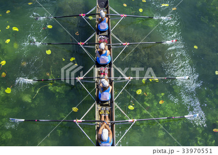 Ladies fours rowing team in race on the lake 33970551