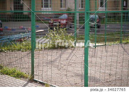 Broken mesh of metal fence of a basketball court Broken mesh of metal fence of a basketball court 34027765
