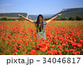 Woman stands with open arms on summer poppy field 34046817