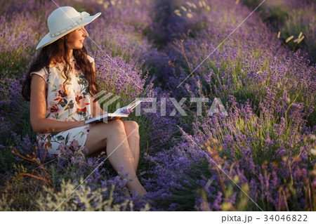 Romantic woman sits with book on lavender field 34046822