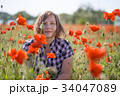 Portrait of smiling woman on poppy field 34047089