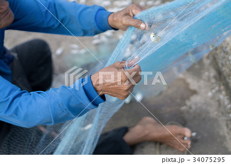 Old Fishermen clearing fisherman net  34075295