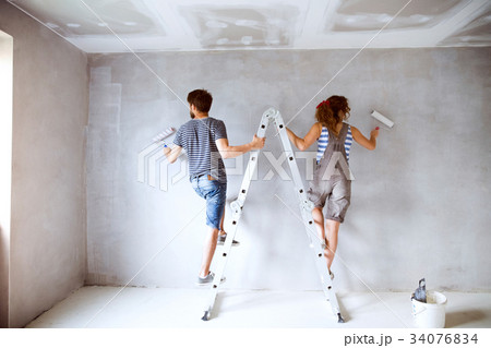 Young couple painting walls in their new house. Young couple painting walls in their new house. 34076834