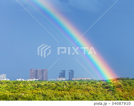 rainbow in blue rainy sky over city and urban park 34087910