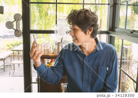 Asian man using smartphone in the coffee shop Asian man using smartphone in the coffee shop 34128300