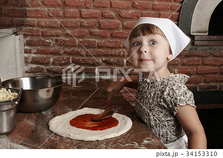 Adding tomato's sauce to pizza. Adding tomato's sauce to pizza. 34153310