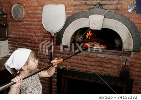 Baby baker takes out pizza from the wood-burning 34153332