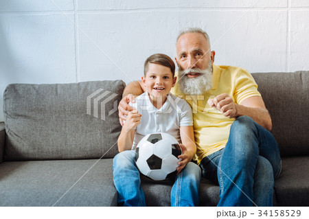 Upbeat grandfather and grandson supporting their Upbeat grandfather and grandson supporting their 34158529