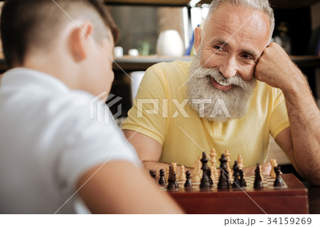 Cheerful senior man smiling at grandson while 34159269