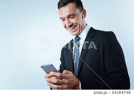 Cheerful joyful man using his smartphone 34164748