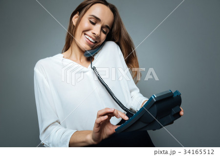 Delighted positive woman dialing a number Delighted positive woman dialing a number 34165512