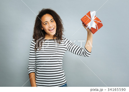 Cheerful international girl showing her present Cheerful international girl showing her present 34165590