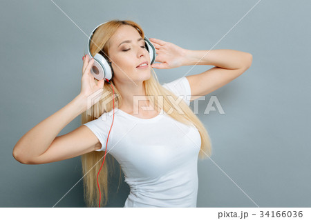 Delighted female person enjoying music 34166036