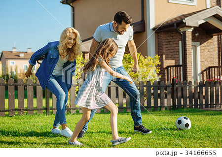 Cheerful family playing football on the backyard Cheerful family playing football on the backyard 34166655