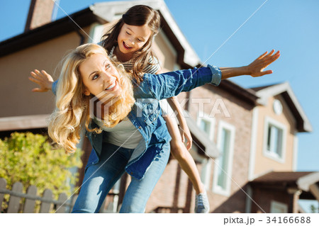 Happy mother carrying her daughter on back Happy mother carrying her daughter on back 34166688