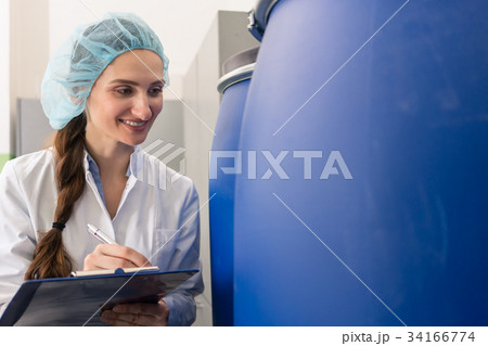 Manufacturing employee writing report during 34166774