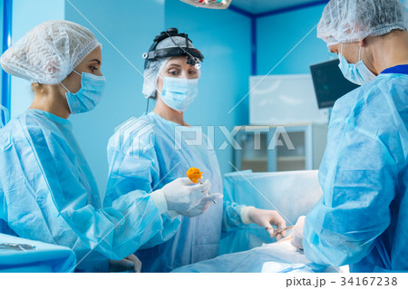 Competent doctor looking at her assistant Competent doctor looking at her assistant 34167238