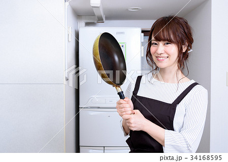 キッチンでフライパンを持つ女性 アップの写真素材