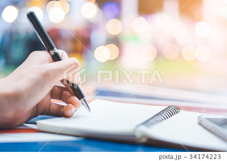 Woman's hand writing on a notebook with a pen Woman's hand writing on a notebook with a pen 34174223