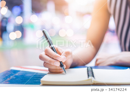Woman's hand writing on a notebook with a pen Woman's hand writing on a notebook with a pen 34174224