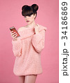 Brunette holding cell telephone. Fashion studio 34186869