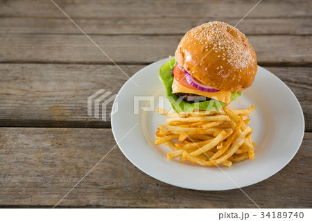 Hamburger, french fries, tomato sauce and glass of beer on chopping board 34189740